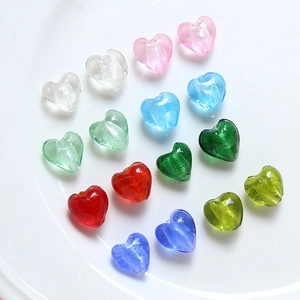 Gros plan de perles en verre colorées en forme de cœur avec feuilles d'or pour DIY