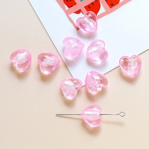 Détail d'une perle cœur rose translucide avec paillettes pour création de bijoux