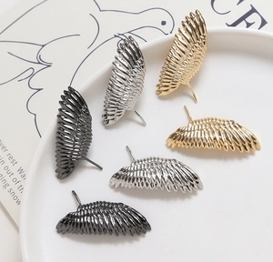 Détail macro de breloques en forme d'ailes dorées et argentées aux textures de plumes