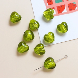 Vue macro de perles en verre coeur vert avec feuilles d'or pour bijoux DIY