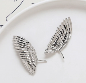 Gros plan de breloques ailes de plumes argentées pour bijoux DIY sur plateau en céramique