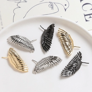Lot de six accessoires bijoux ailes de plumes en or, argent et noir sur céramique blanche