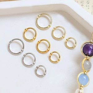 Twisted gold and silver hoop earrings with colorful pearl charms on a white tray