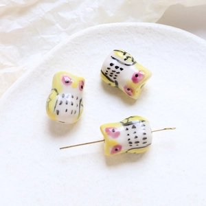 Close-up of yellow owl ceramic beads for DIY jewelry making with smooth glazed finish