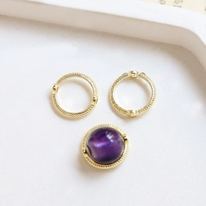 Detailed view of gold-plated textured round charm frames and purple gemstone for DIY jewelry