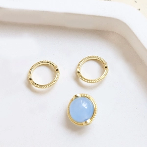 Macro detail of gold-plated twisted lace rings and light blue bead for jewelry making