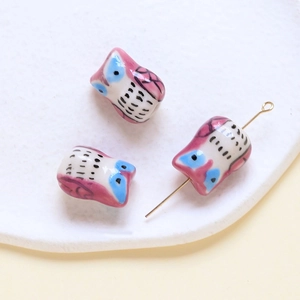 Detailed view of handmade owl ceramic beads in pink and blue for DIY jewelry crafting