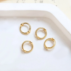 Detail of gold-plated twisted rope beads rings for DIY jewelry making on white ceramic