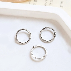 Macro shot of silver scalloped metal bead rings for DIY jewelry on a white tray