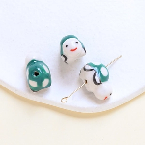 Detailed close-up of handmade ceramic beads with painted smile faces on a white tray
