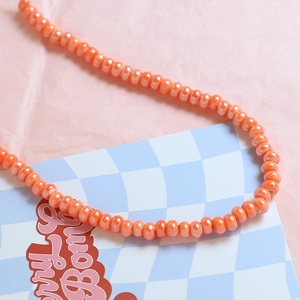 Close-up of glossy orange ceramic beads for DIY jewelry making and handmade necklaces