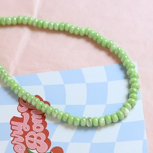 Detailed macro view of grass green macaron ceramic beads with glossy iridescent texture