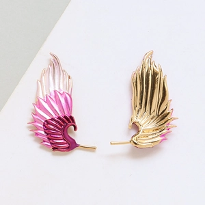 Detail of asymmetric wing stud earrings with pink gradient and gold plated finish