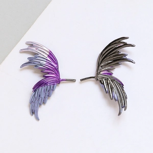Detailed macro view of asymmetric purple and silver metal wing ear cuffs with feather texture