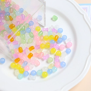 Perles en verre macaron translucides colorées de formes variées sur une assiette en céramique
