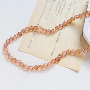 Gros plan de perles en verre facetté ambre avec reflets champagne sur papier vintage