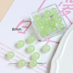 Détail de perles en verre vert clair 8mm pour bijoux DIY dans une boîte transparente