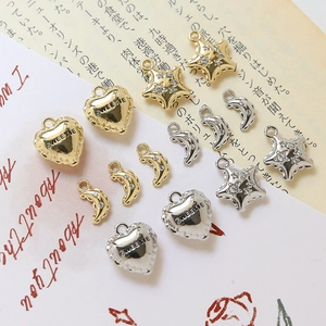 Macro shot of gold and silver heart, star, and moon charms with zircon inlays for DIY jewelry