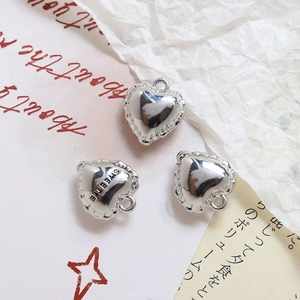 Macro view of silver heart charms with scalloped edges and Sweetie engraving for DIY jewelry