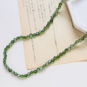 Détail de perles en cristal de verre facetté vert irisé pour la création de bijoux