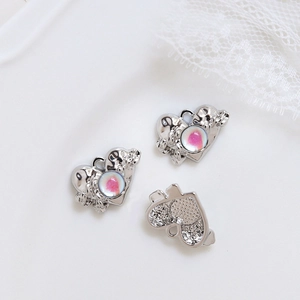 Détail macro de pendentifs planète cœur avec zircons colorés et finition en alliage