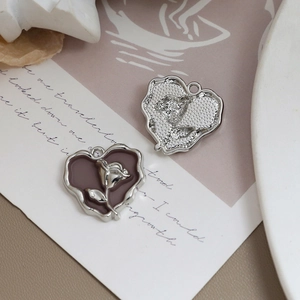 Makroansicht von Vintage-Herzanhängern mit Rosenrelief in Silber und Emaille-Finish