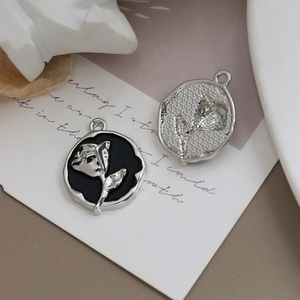 Nahaufnahme von Vintage Rosen Emaille Anhängern für DIY Schmuck auf antikem Hintergrund