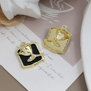 Details von quadratischen Rosen-Anhängern mit schwarzer Emaille und goldenem Reliefdesign