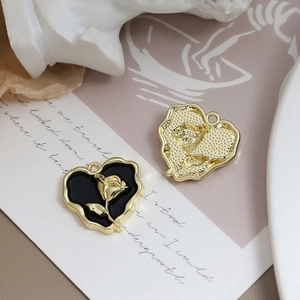 Detail von herzförmigen Anhängern mit goldenen Rosen-Reliefs und Emaille-Finish im Vintage-Stil