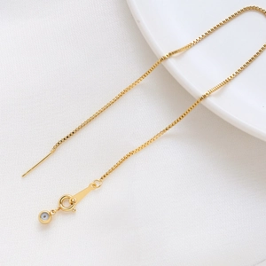 Détail d'une chaîne box plaquée or 14k avec charme œil bleu et fermoir mousqueton