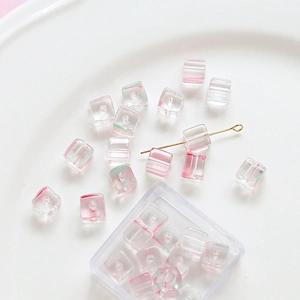 Close-up of square glass beads with pink and green swirls for DIY jewelry making