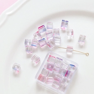 Macro shot of iridescent cube glass beads for DIY jewelry making in a decorative dish