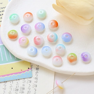 Colorful gradient donut glass beads for DIY jewelry making on white ceramic plate