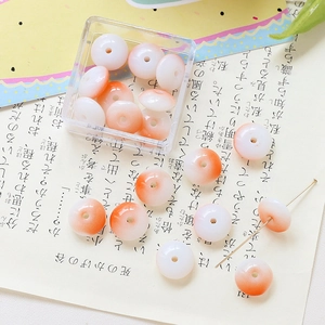 Macro view of gradient orange-pink flat round beads in a clear acrylic storage box