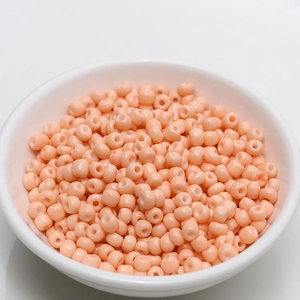 Macro detail of 4mm dusty pink porcelain seed beads for DIY jewelry making in a white bowl