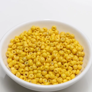 Macro shot of 4mm bright yellow beads for DIY jewelry making in a white ceramic bowl