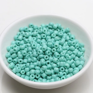 Close-up of 4mm mint green seed beads in a white bowl for DIY jewelry making