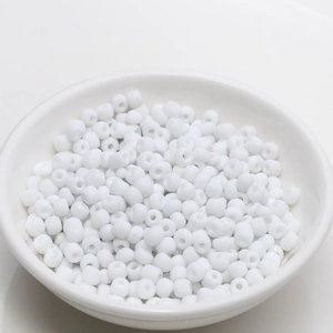 Macro detail of 4mm white glossy beads in a ceramic bowl for DIY jewelry making