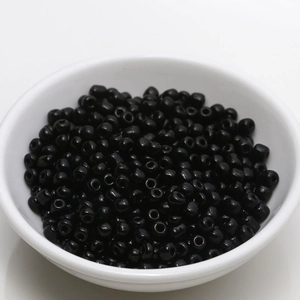 Detailed view of 4mm glossy black ceramic beads piled in a white porcelain bowl for DIY jewelry