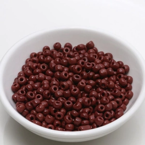 Macro shot of 4mm polished dark brown beads in a white bowl for DIY jewelry making
