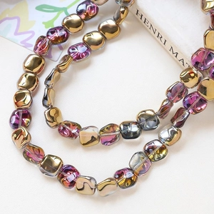 Macro shot of iridescent square glass beads with gold and fuchsia metallic finish