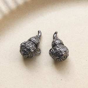 Detalle de colgantes de calabaza en metal gris oscuro con carácter Fu y patrones de moneda