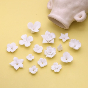 Diverse witte matte keramische bloemkralen voor DIY sieraden op gele achtergrond