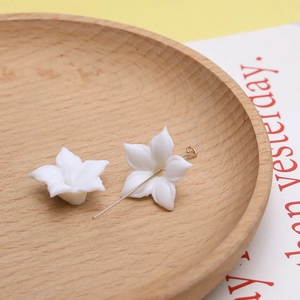 Macro-opname van witte keramische bloemen met gouden metalen pin voor DIY-sieraden maken