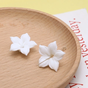 Macro-detail van witte keramiekachtige bloemkralen met metalen pen voor DIY-sieraden