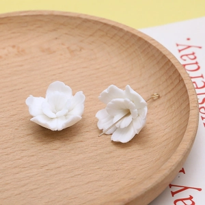 Macro-opname van witte harsbloembedeltjes en een metalen naald op een ronde houten tray
