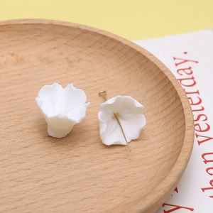Detail van witte hars bloembedeltjes met metalen pinnen voor DIY handgemaakte sieraden