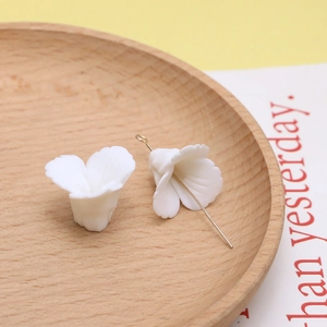 Macro-opname van witte hars bloembedeltjes met gouden haken voor DIY-sieraden maken