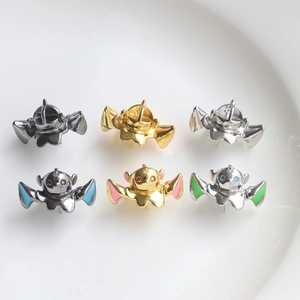 Close-up of six colorful DIY metal charms in bat and monster shapes on white ceramic