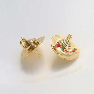 Macro detail of gold-plated cat ear hat earrings with red bow and fine metallic texture
